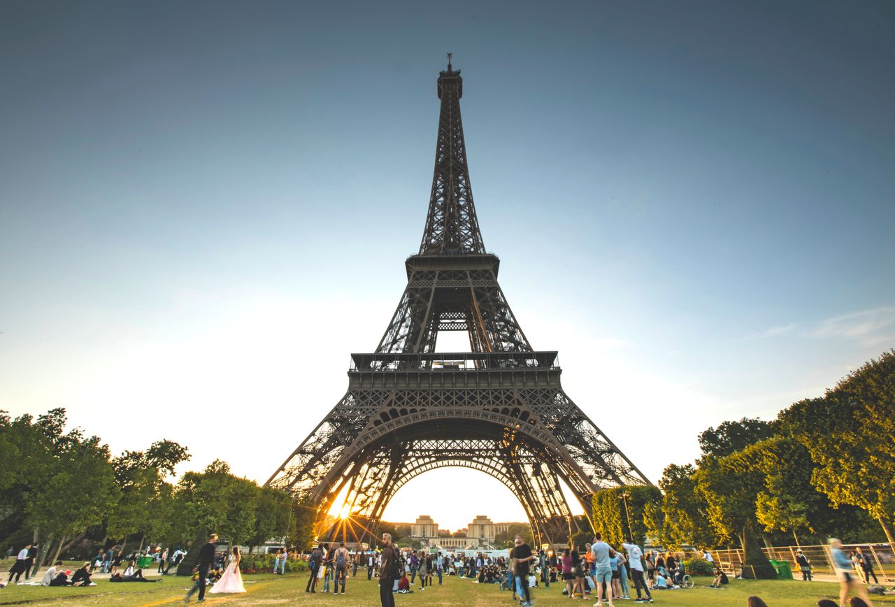 Tourists enjoy a sunny day at the Eiffel Tower in Paris, France.